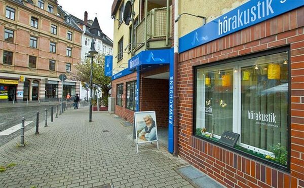 Geschäft für Hörakustik mit Schaufenster und Werbeschild in einer belebten Stadtstraße.