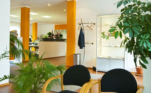 Modernes Büro mit Wartebereich, Pflanzen, Garderobe und heller, freundlicher Atmosphäre.